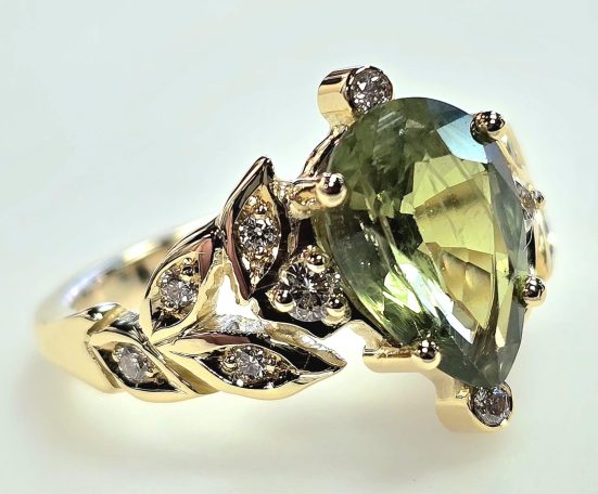 Ovale, groene ring met bladvormige details en sprankelende diamanten.